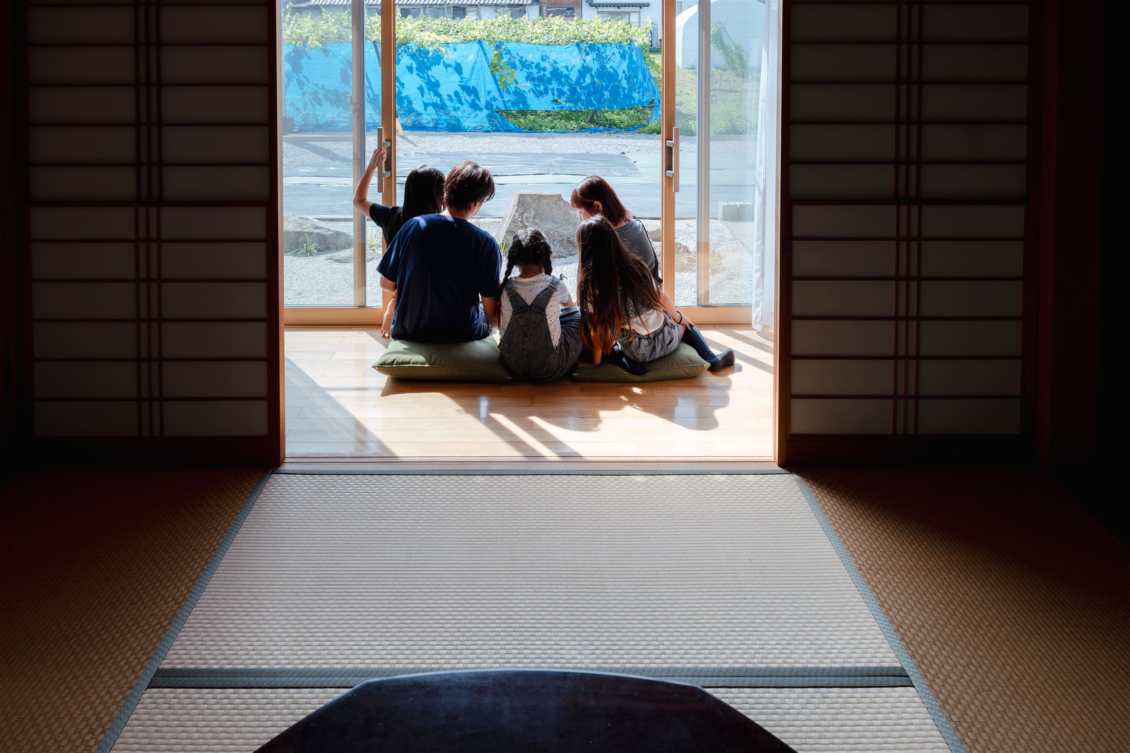 縁の和室。障子を開けた縁側から外を眺める家族の後ろ姿