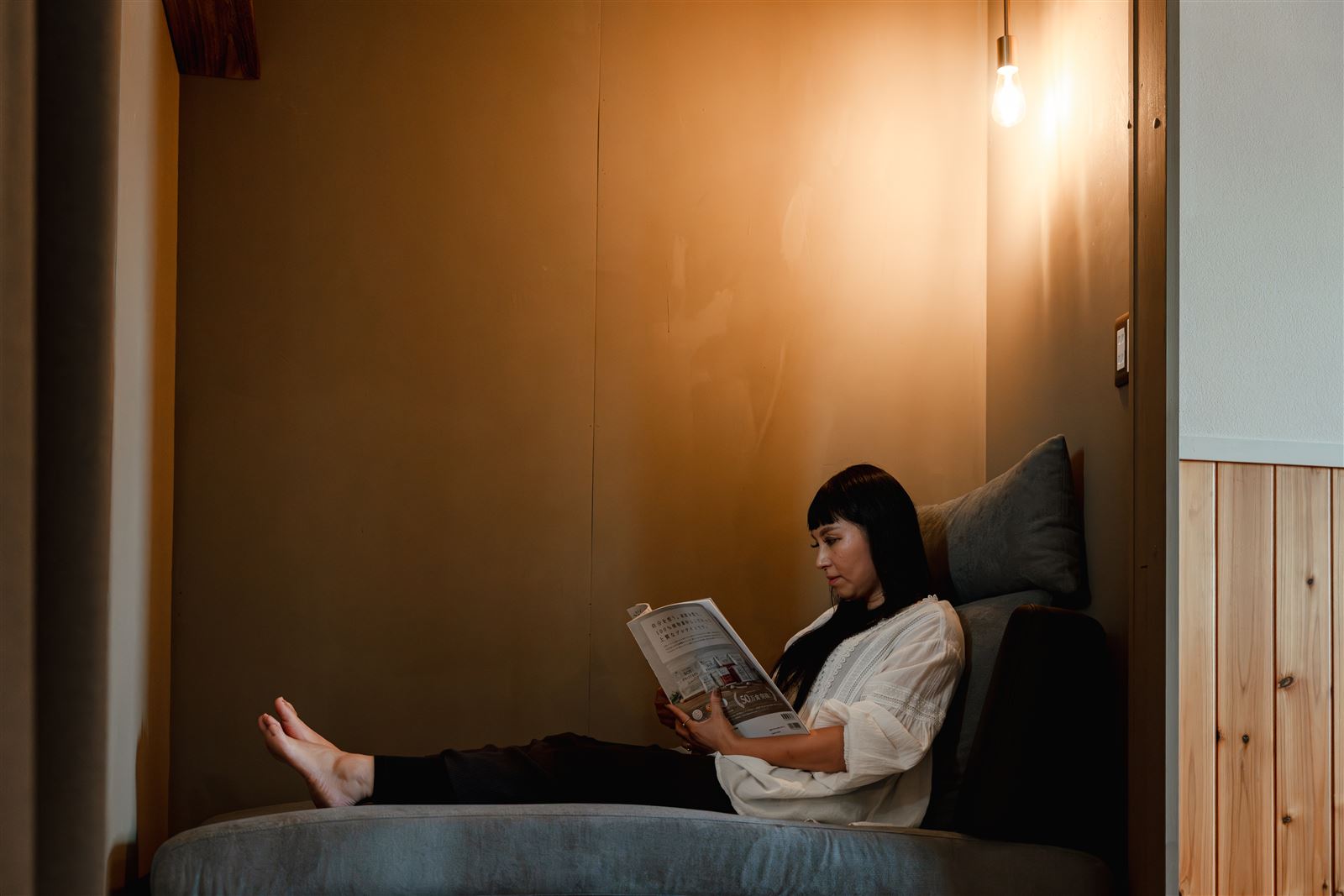 壁にくぼんだ椅子で本を読む女性